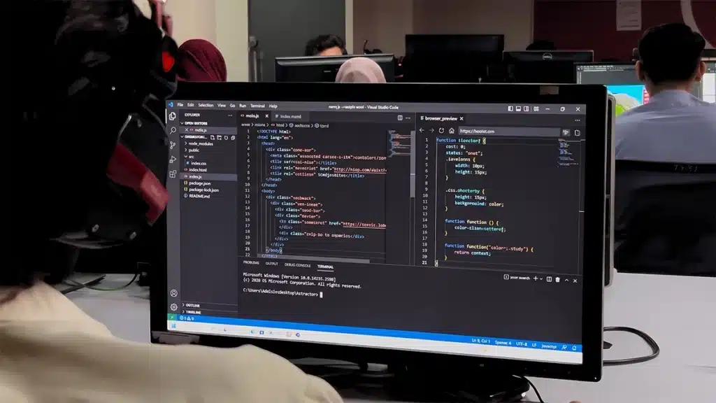 Web development course in Rawalpindi — a student writing HTML and JavaScript in a code editor in a computer lab